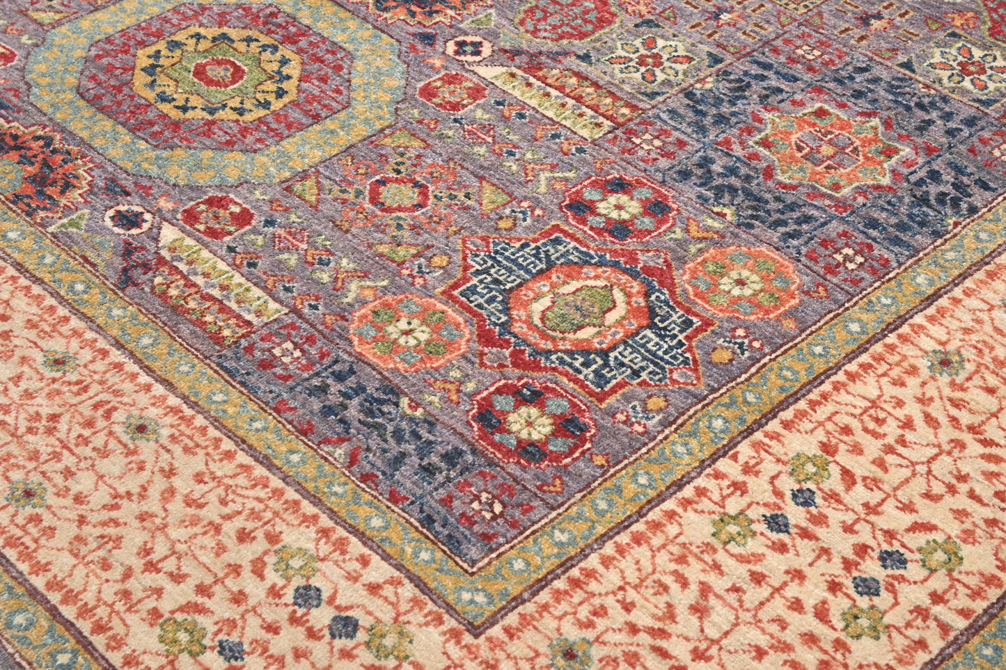 Close-up of a patterned rug with geometric designs in red, blue, and beige.