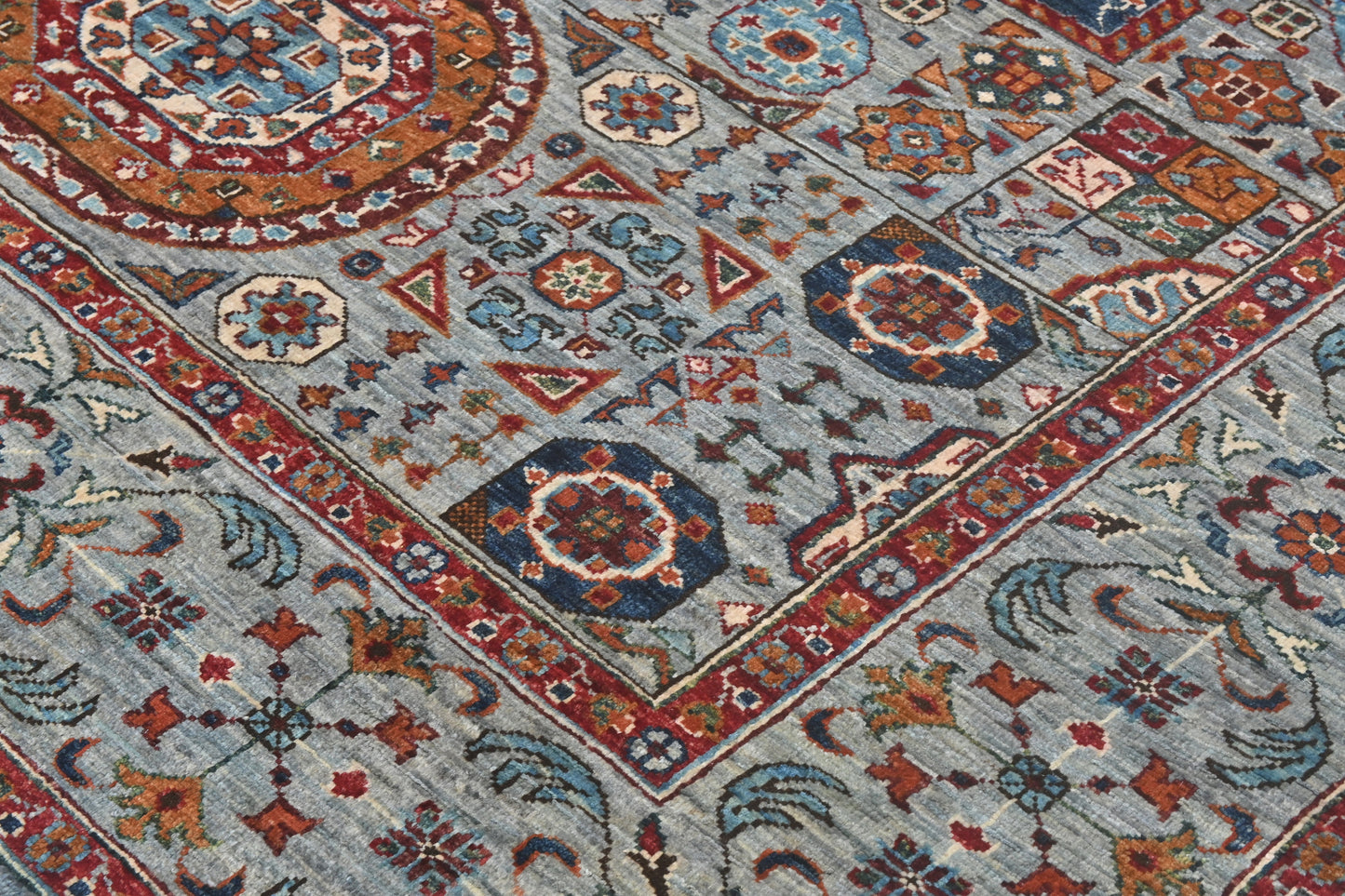 Close-up of a patterned rug with geometric designs in blue, red, and brown.