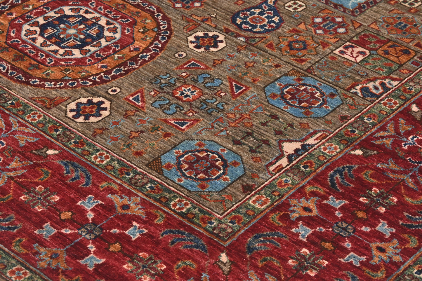 Close-up of a patterned rug with geometric designs in red, blue, and brown.