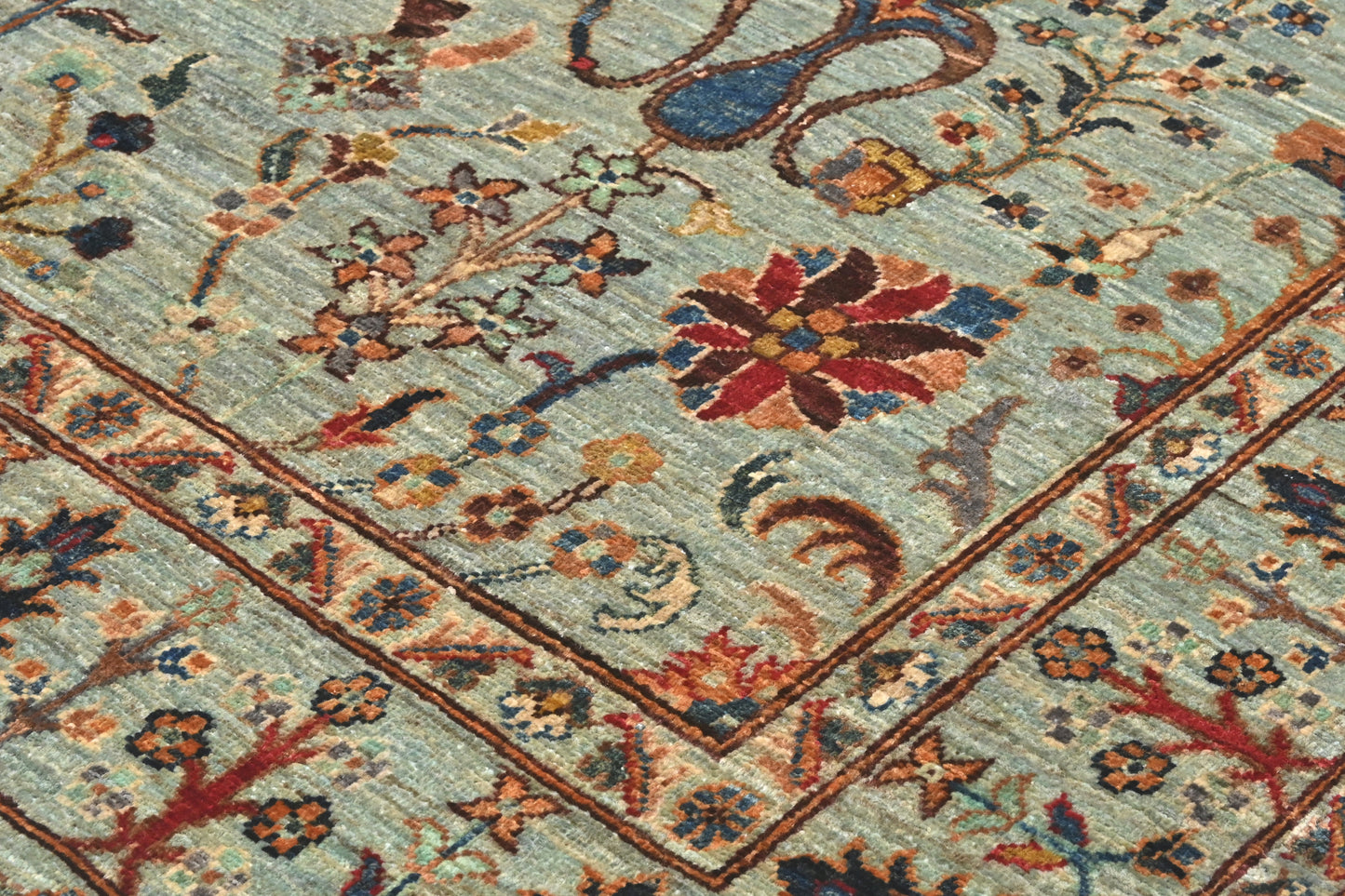 Close-up of an intricately designed floral rug with a light blue background.