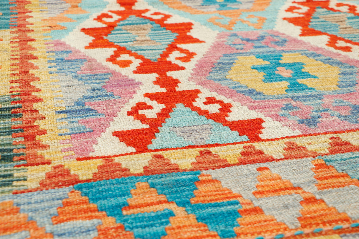 Afghan Kilim rug by eastofhere, 127x81cm, featuring traditional geometric patterns in vibrant colors, displayed on a wooden floor.