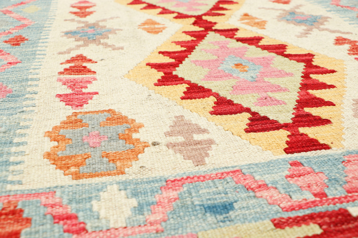 Afghan Kilim rug by eastofhere featuring geometric patterns in vibrant colors, measuring 117x78cm, laid out on a wooden floor.