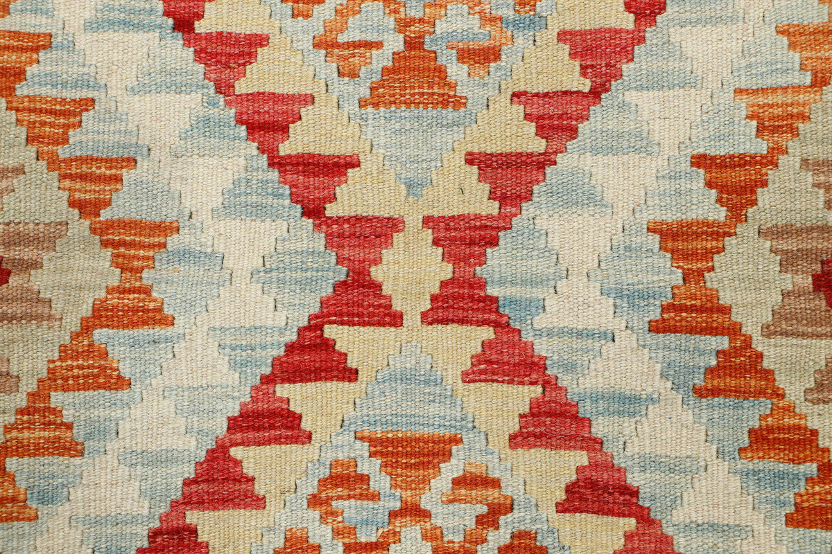 Afghan Kilim rug by eastofhere, 116x79cm, featuring traditional geometric patterns in vibrant colors, displayed on a wooden floor.