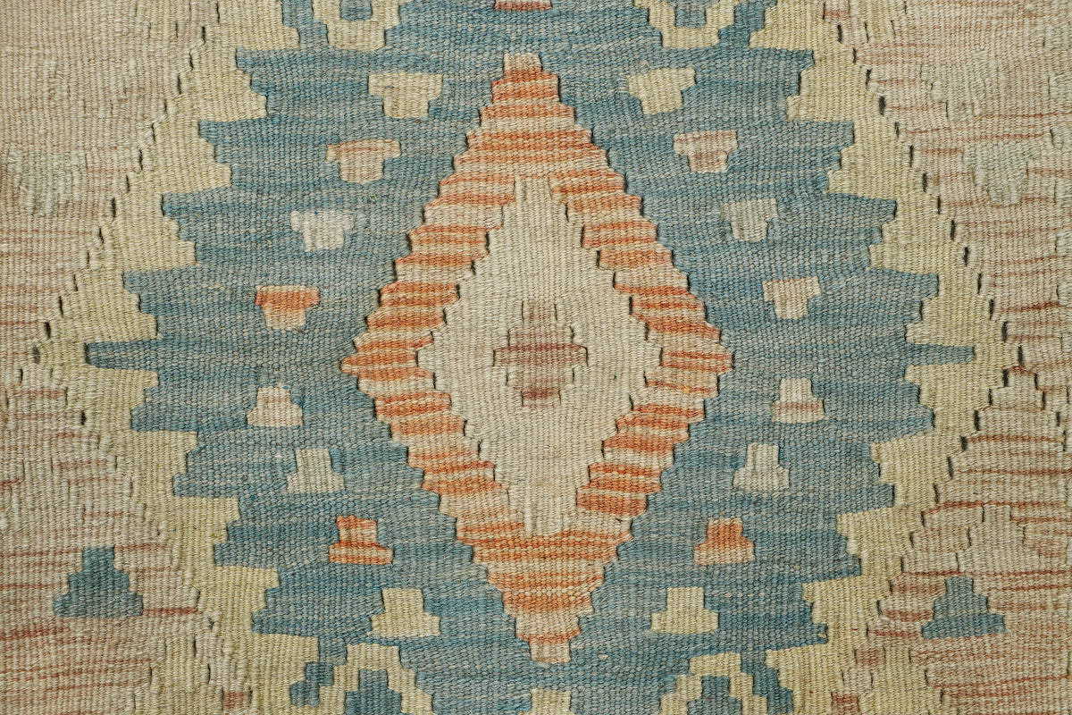 Close-up of a woven textile with a geometric diamond pattern in muted blue, beige, and terracotta orange.
