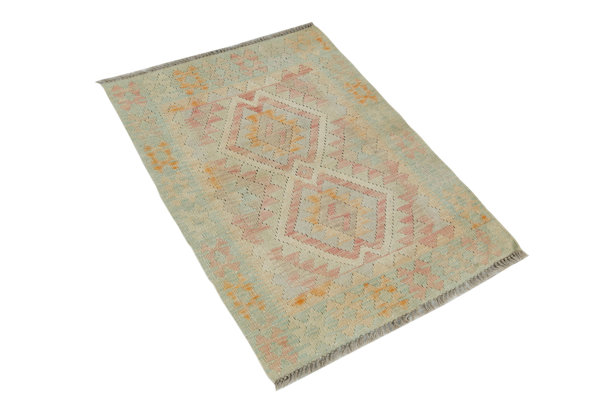 A rectangular kilim rug with a geometric diamond pattern in muted pastel shades of pink, orange, and sage green on a cream background, shown on a plain white background.