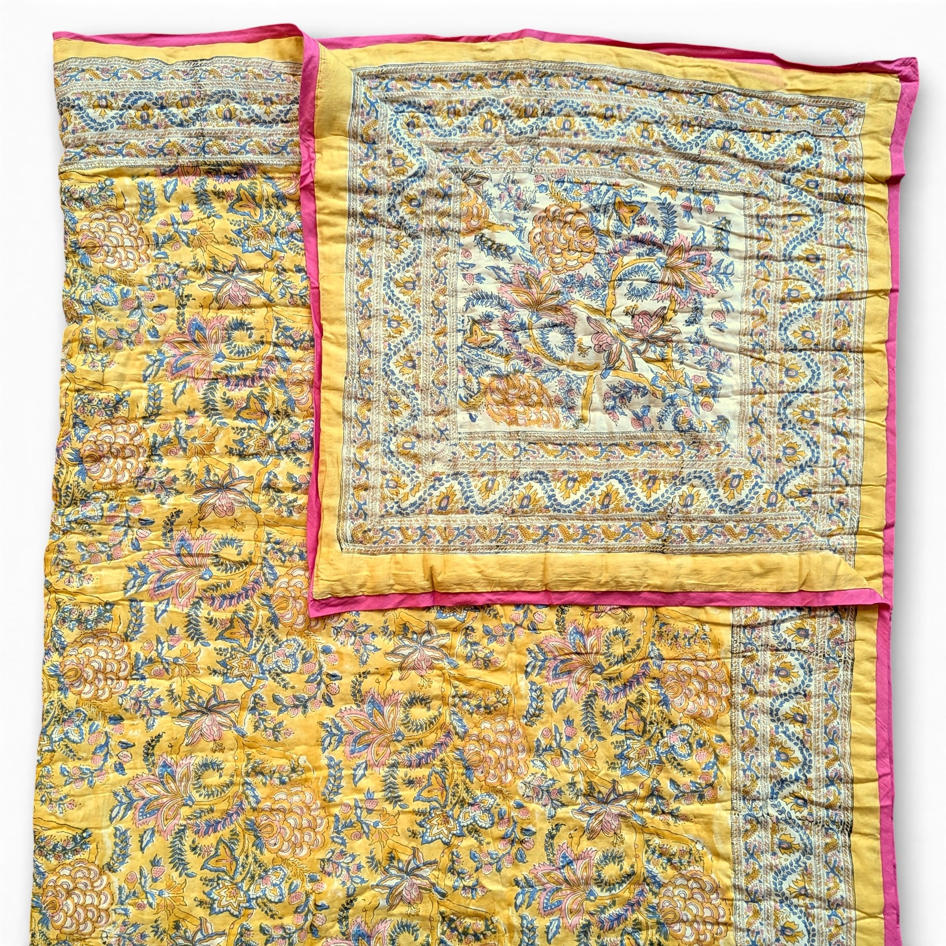 Yellow floral patterned quilt with pink border on a white background