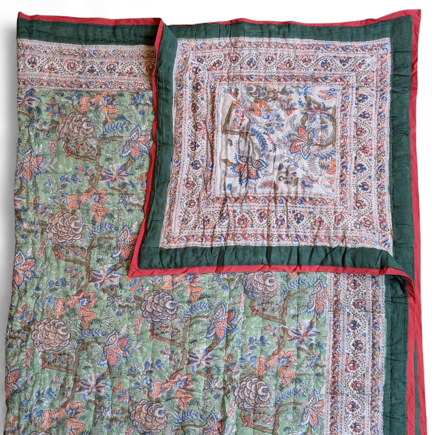 Decorative quilt with intricate patterns and a red border on a white background