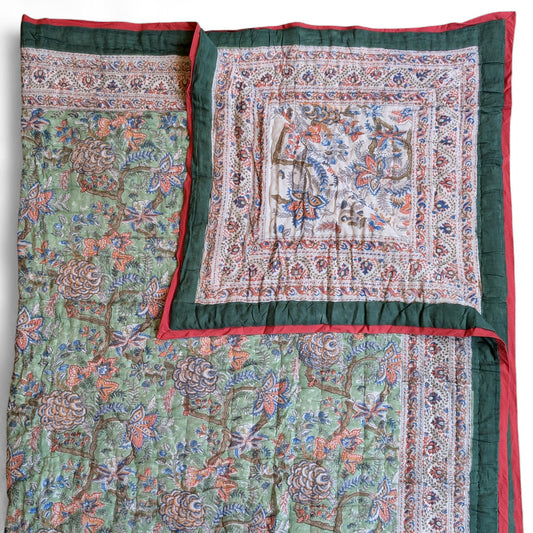 Decorative quilt with intricate patterns and a red border on a white background