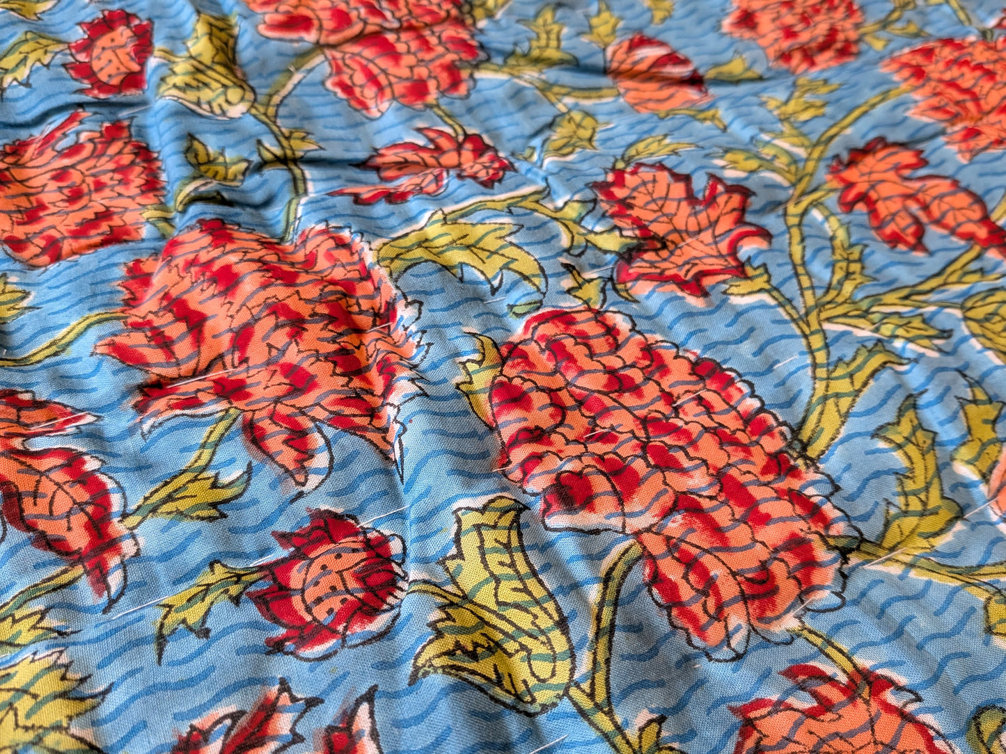 Floral patterned fabric with red and yellow flowers on a blue background