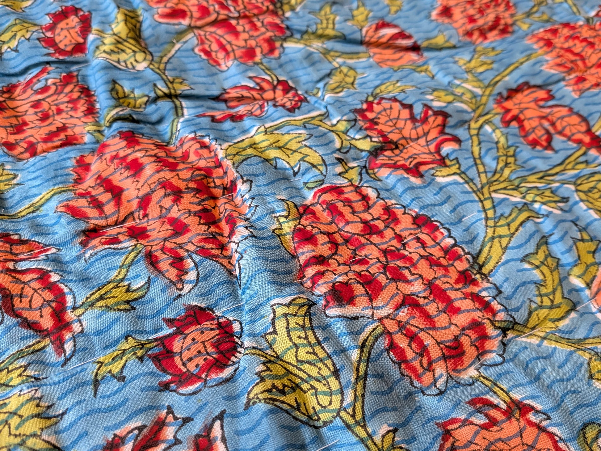 Floral patterned fabric with red and yellow flowers on a blue background
