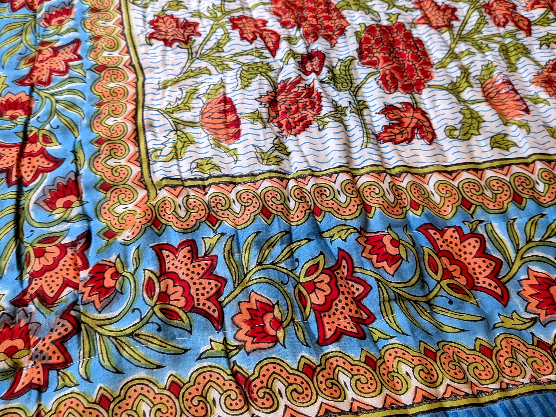 Colorful floral patterned fabric with red flowers on a blue background