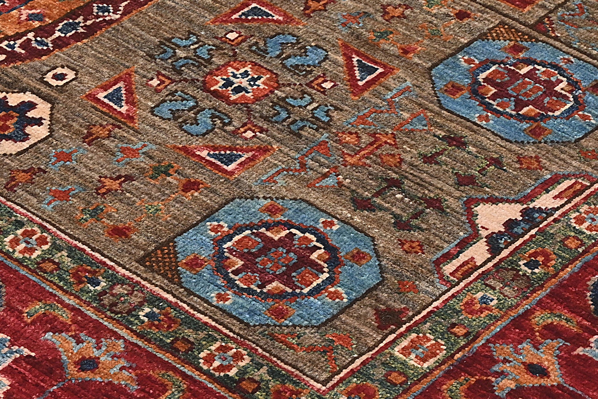 Close-up of a patterned rug with geometric designs in red, blue, and brown.