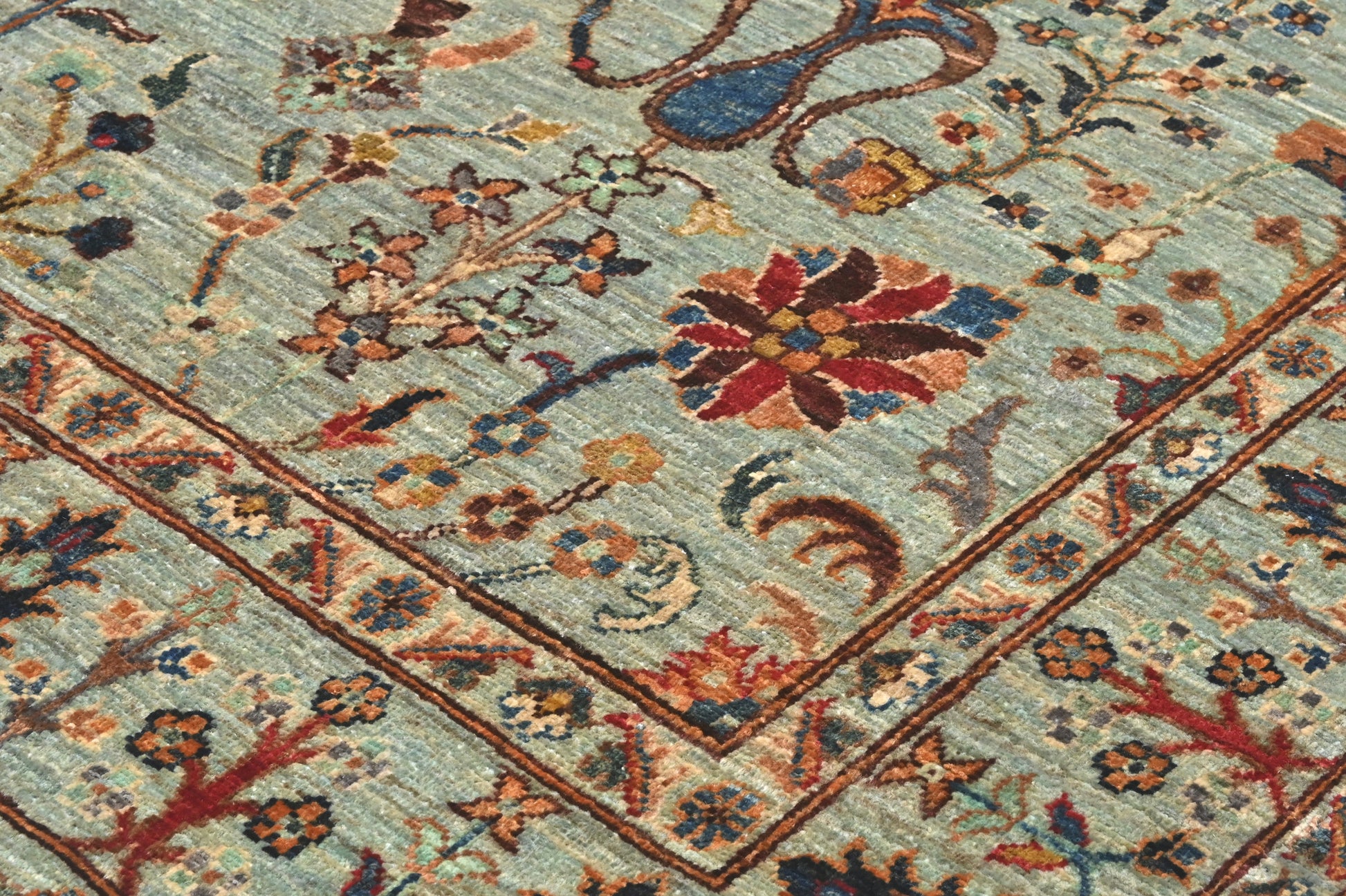Close-up of an intricately designed floral rug with a light blue background.