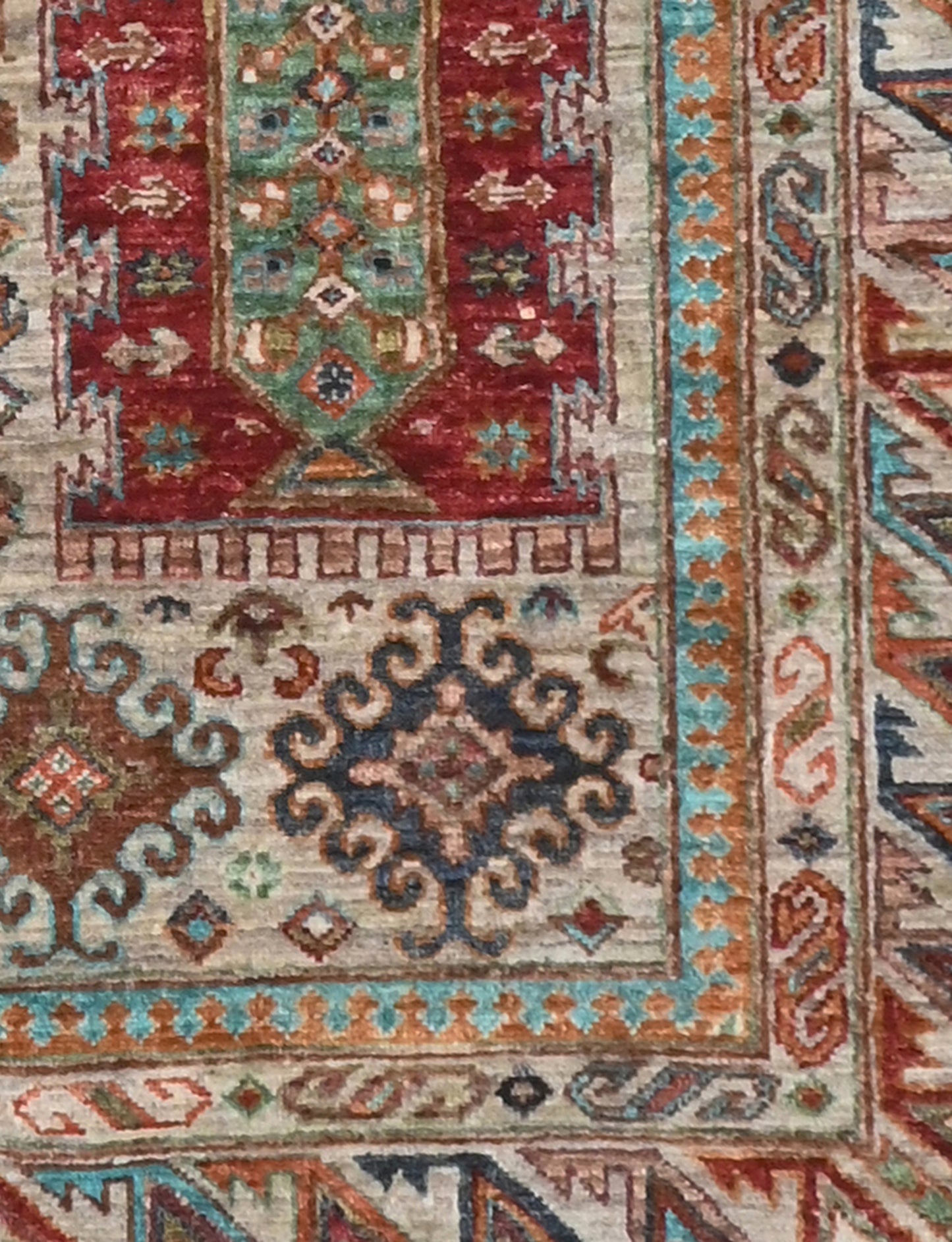 Close-up of a patterned rug with intricate designs in red, blue, and beige.