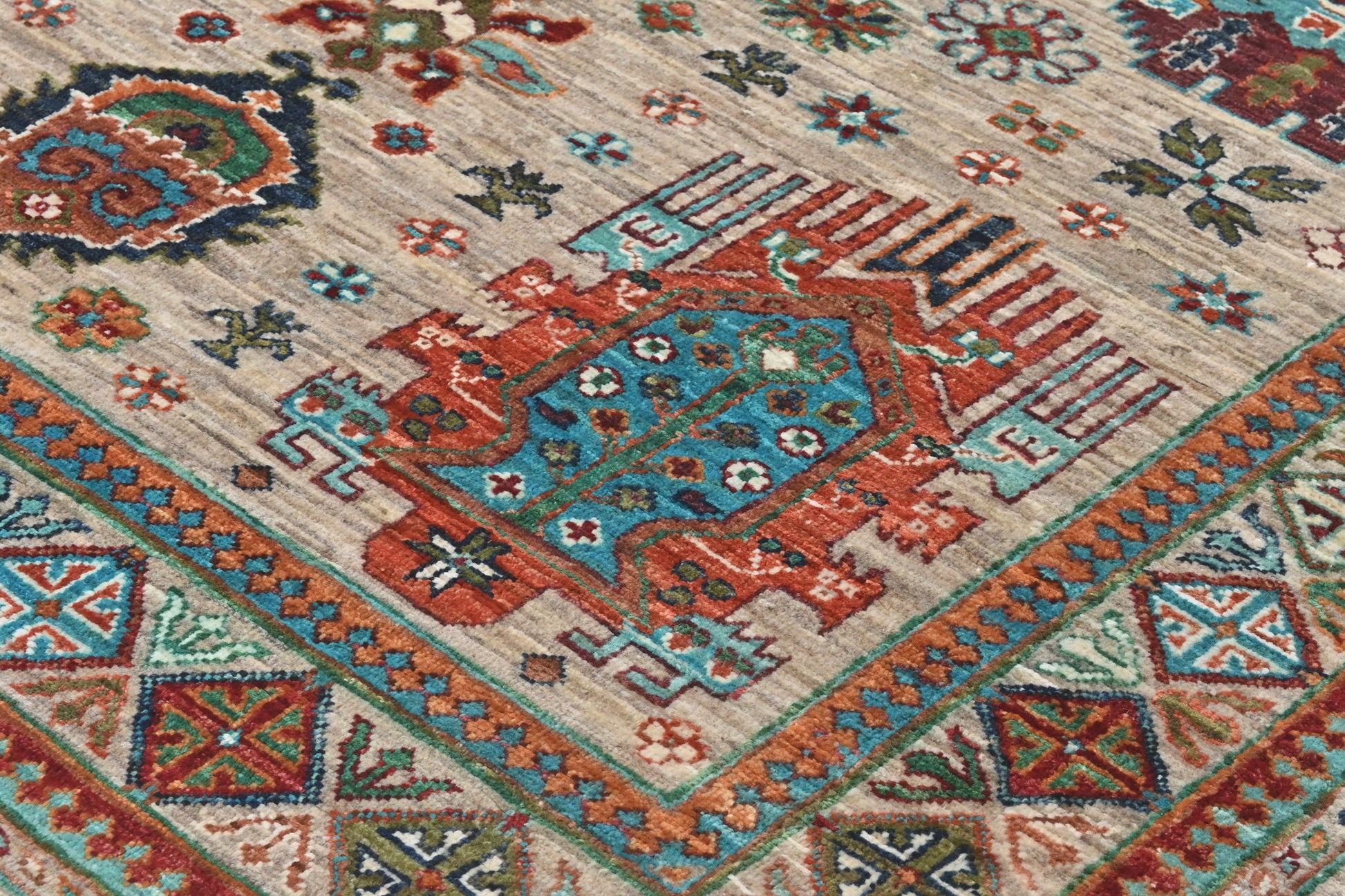 Close-up of a patterned rug with geometric designs in red, blue, and beige.