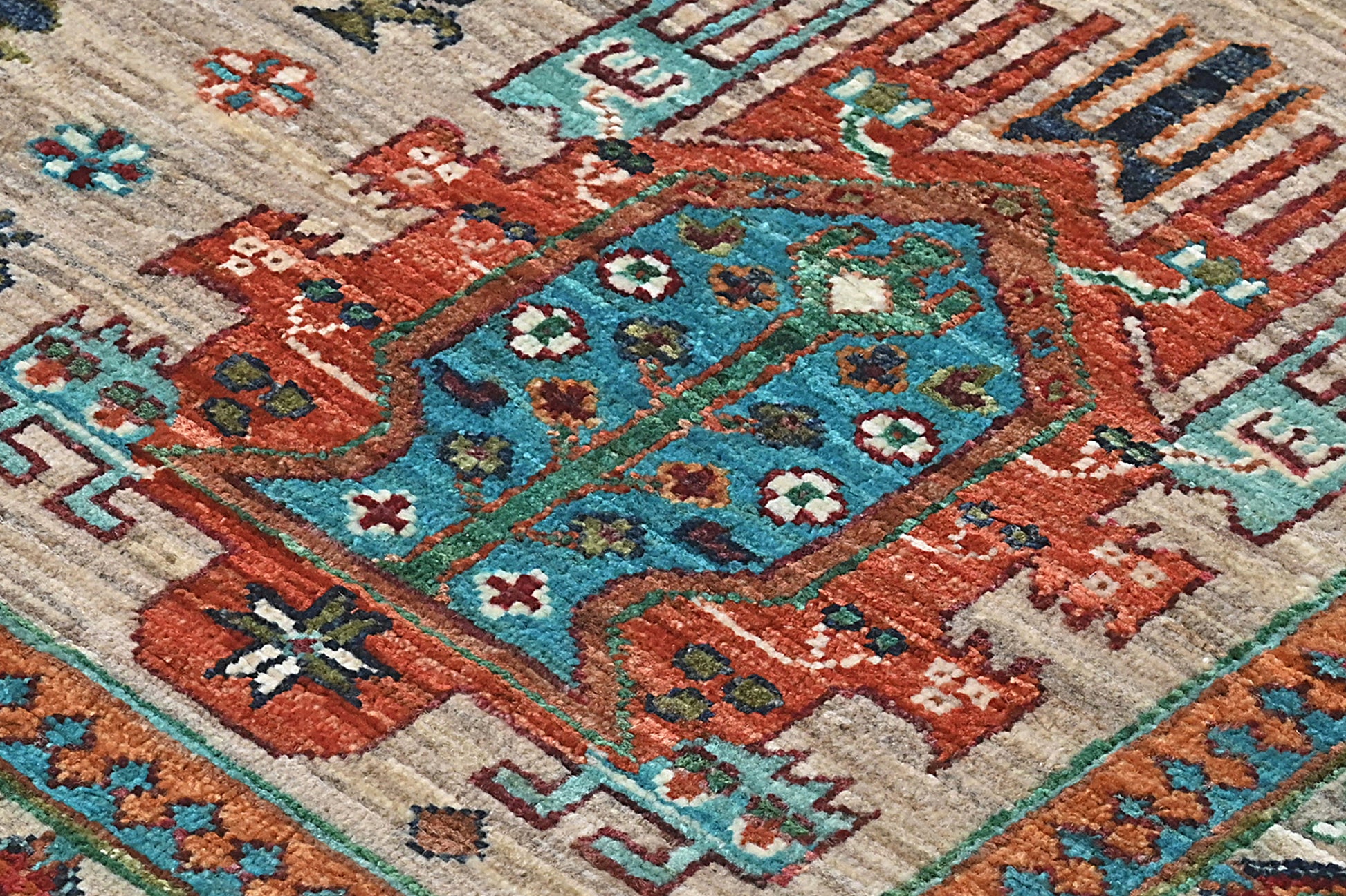 Close-up of a patterned rug with intricate designs in red, blue, and beige.