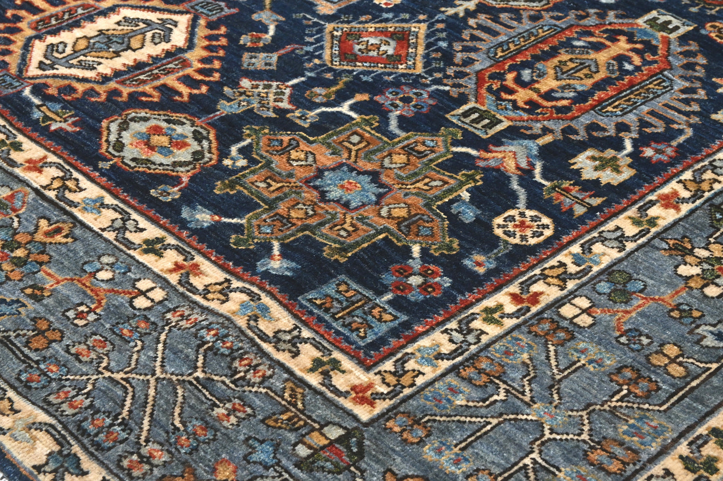Close-up of a patterned rug with geometric designs in blue, red, and beige.