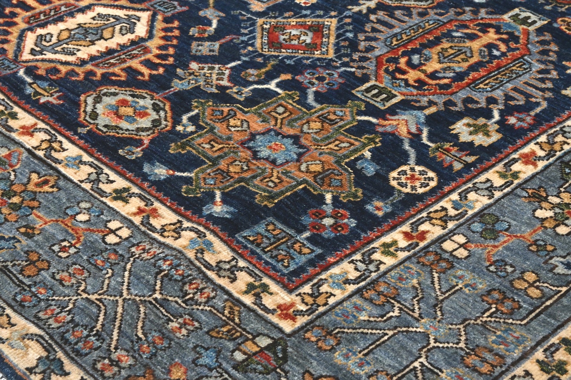 Close-up of a patterned rug with geometric designs in blue, red, and beige.