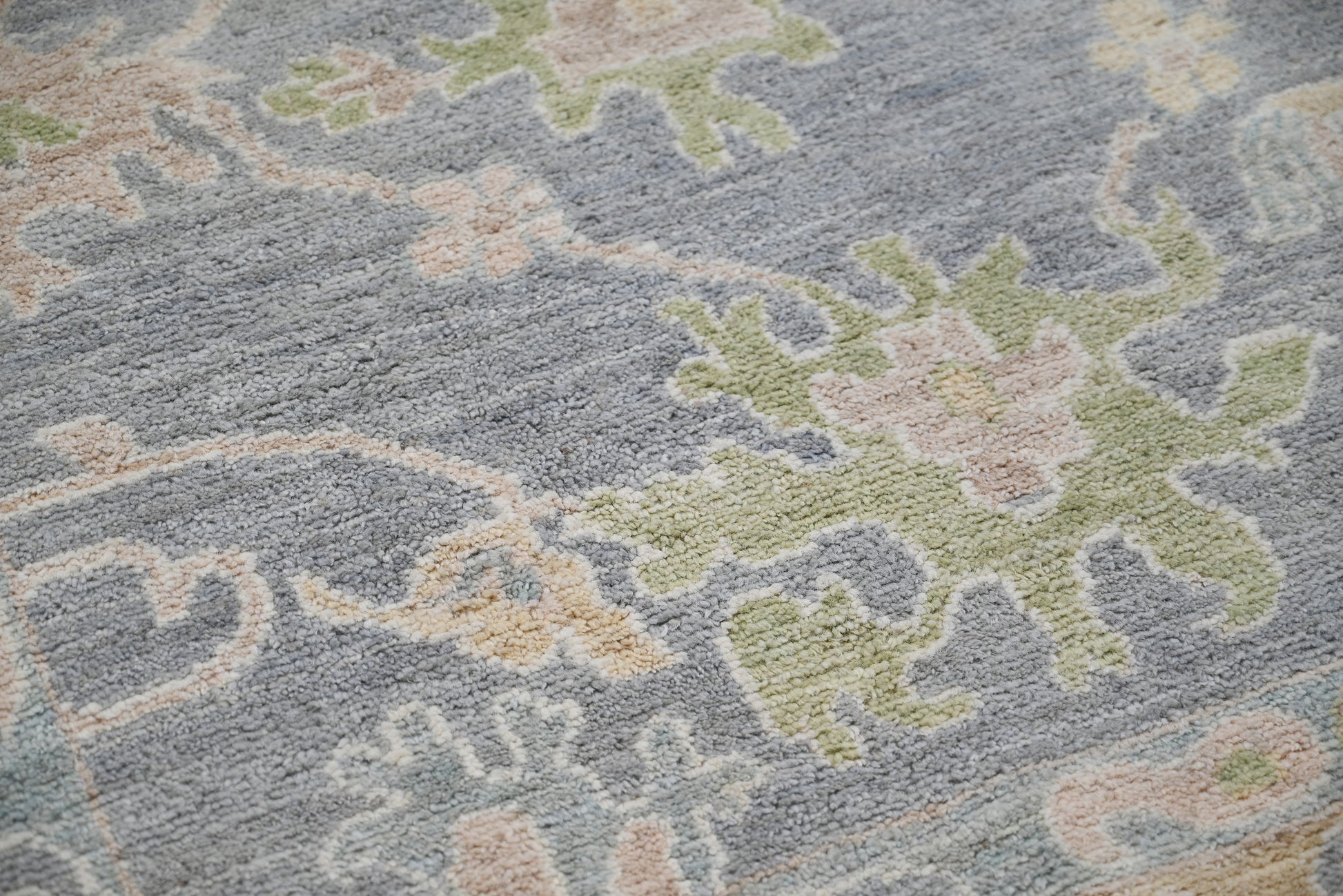 Close-up of a textured rug with abstract patterns in gray, green, and beige.
