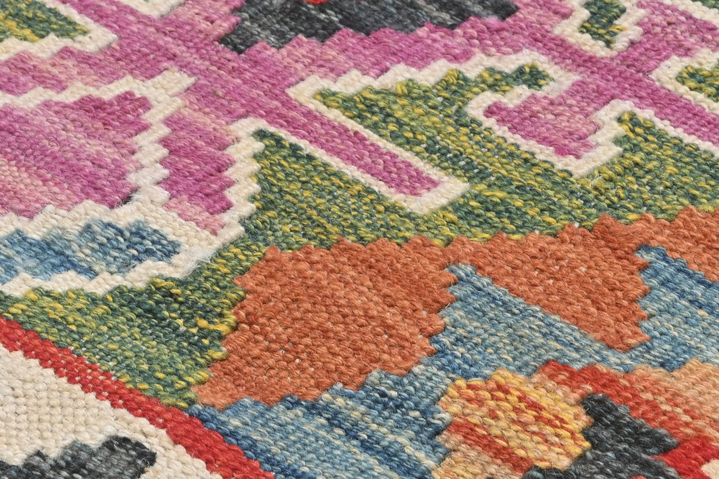 Close-up of a colorful geometric patterned rug with vibrant colors.
