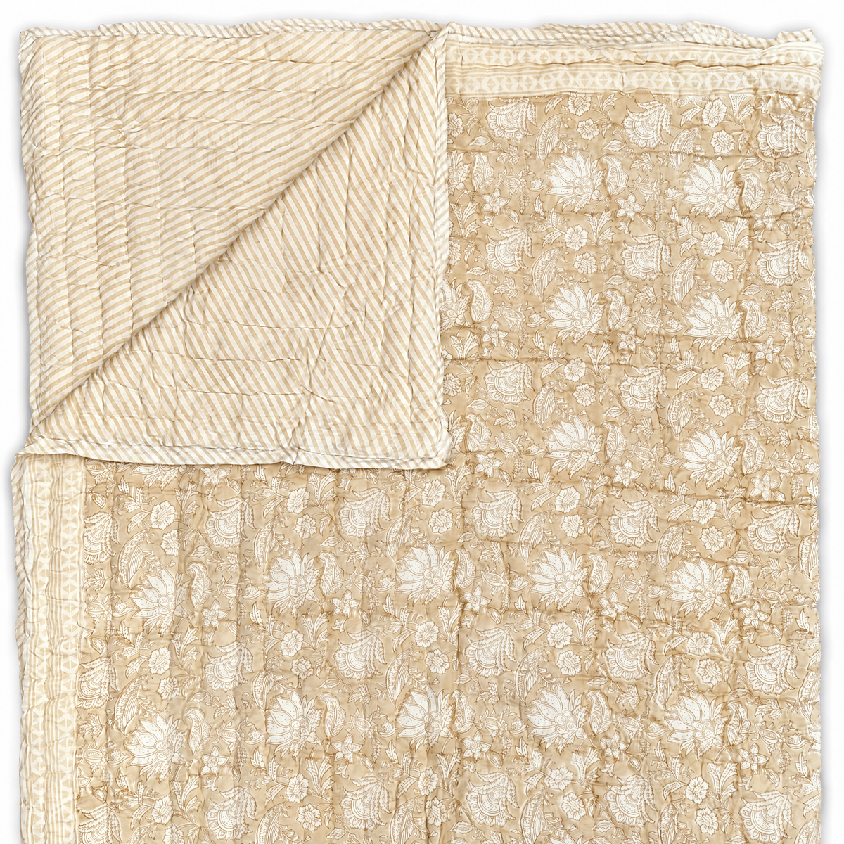 A beige quilted cotton blanket with a white floral and paisley pattern, shown folded to display both its patterned front and stitched back.